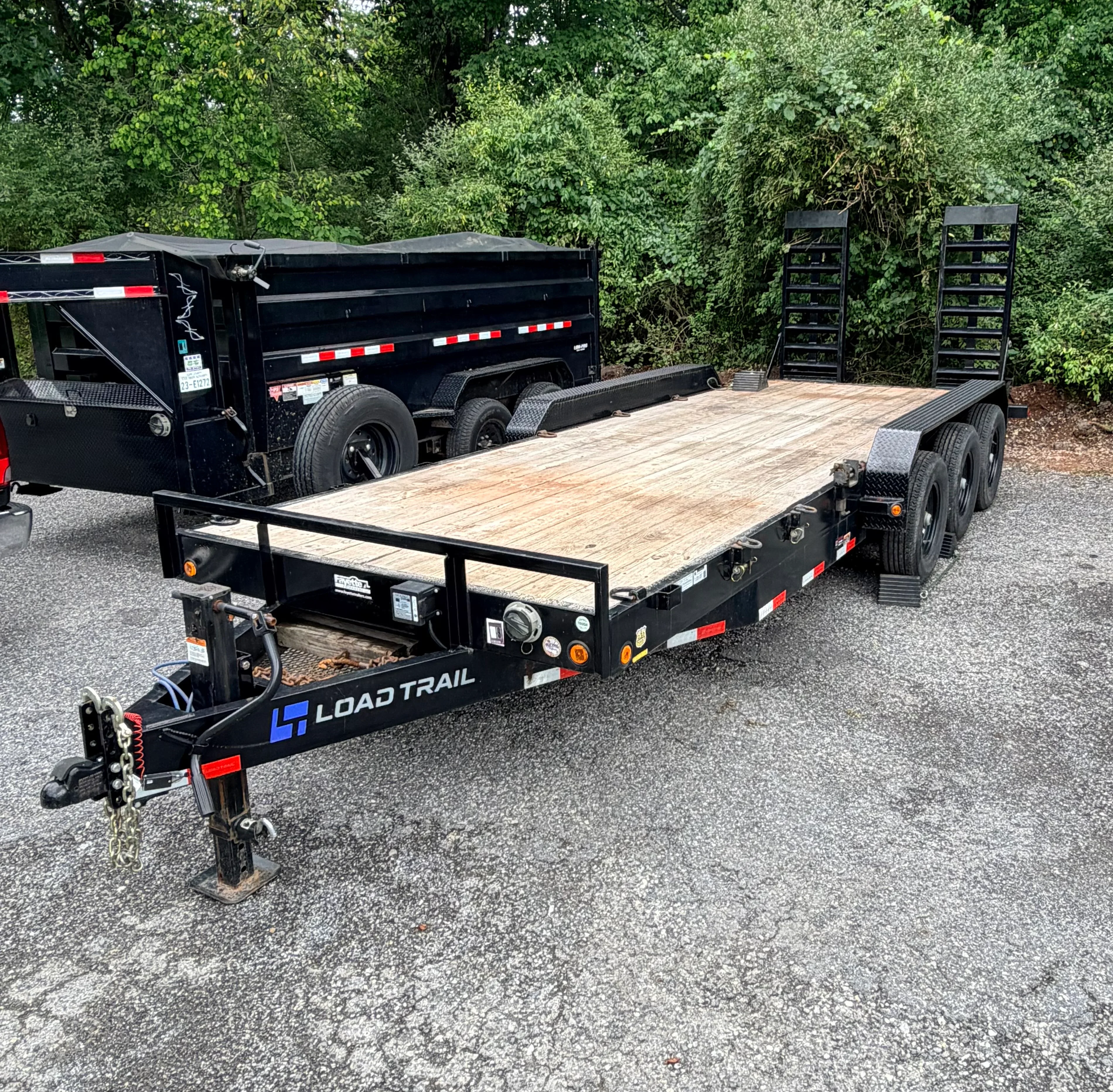 Tandem axle utility trailer with wood deck, black steel frame, and safety lights